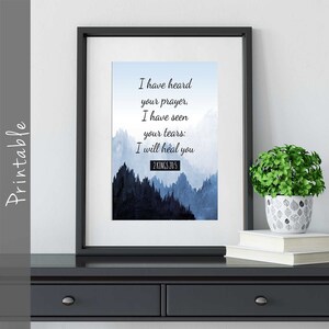 Op de afbeelding: Een printbare wandkunstprint met een blauwe aquarelbergachtergrond en de tekst "Ik heb je gebed gehoord, ik heb je tranen gezien: Ik zal je genezen 2 KONINGEN 20:5".