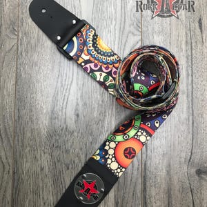May include: A guitar strap featuring a vibrant, multicolored geometric and floral pattern on a dark background. The strap includes black leather ends with metal rivets and a circular silver-toned emblem displaying the Rock Altar logo with a red star.