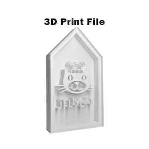 May include: A white 3D print file featuring a cat face design with the text "JELLYCAT" below. The design is set within a house-shaped frame, with the words "3D Print File" at the top.
