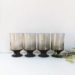 May include: Set of four vintage brown glass tumblers with black bases. The glasses have a frosted, ombre effect.