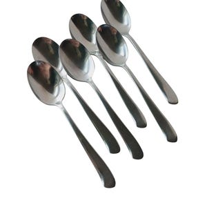 May include: Six silver spoons arranged in a staggered pattern, with the handles pointing to the right.