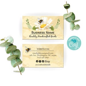 Può includere: Due biglietti da visita con un design a tema ape e margherita. La carta in alto recita "Business Name" e "Quality Handcrafted Goods". La carta in basso include informazioni di contatto, un sito web e icone di social media. Lo sfondo è giallo chiaro con un motivo a nido d'ape.