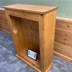 May include: A wooden cabinet with a shelf and a small sign that says "Yellow Woodcraft". The cabinet is made of unfinished pine wood and has a rustic look.