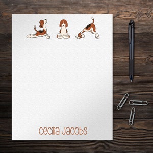 May include: White stationery with a brown border and the text "cecilia jacobs" at the bottom. Three illustrations of brown and white dogs in different yoga poses are at the top of the page.