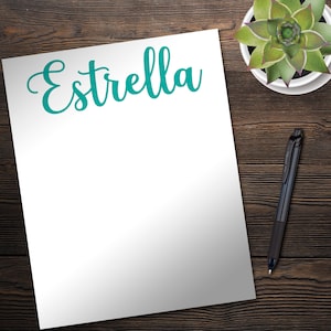 May include: A white sheet of paper with the word "Estrella" written in teal cursive lettering.