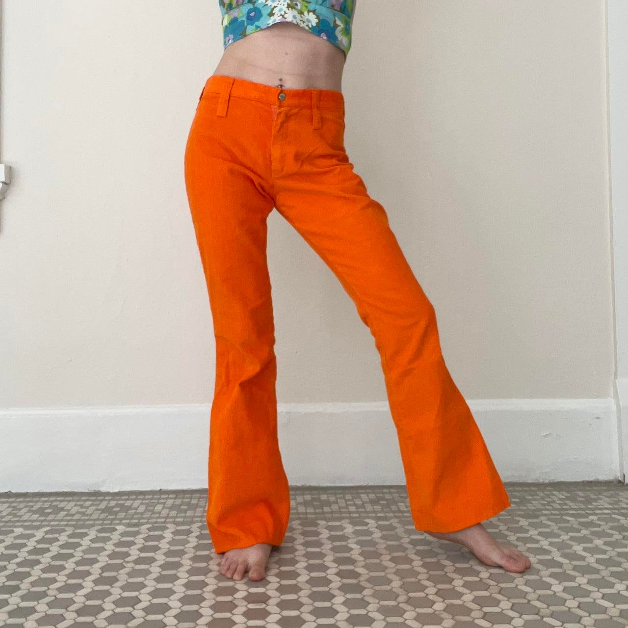 Women Dressed In Varying Shades Of Orange And Bell Bottom Pants