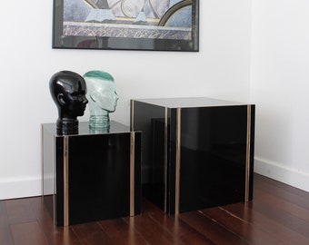 May include: Two black end tables with gold trim, one slightly taller than the other.  The tables are topped with decorative glass and ceramic heads.