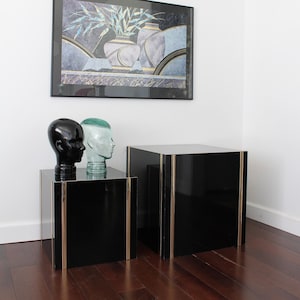 May include: Two black end tables with gold trim, one slightly taller than the other.  The tables are topped with decorative glass and ceramic heads.