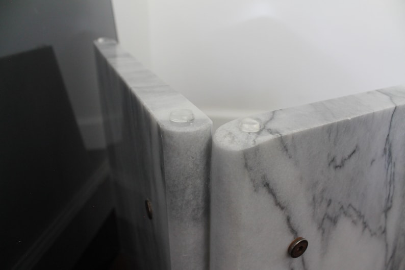 May include: Close-up of a white marble table with clear rubber feet. The table is made of several pieces of marble that are joined together.