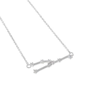 May include: A silver-toned necklace featuring the Aries constellation design. The pendant is a stylized representation of the Aries symbol, with small, clear gemstones set along the lines. The chain is delicate and also silver-toned.