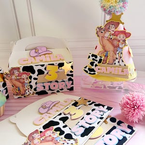 Peut inclure: D&eacute;corations de f&ecirc;te sur le th&egrave;me de la vache, avec les inscriptions "Camila" et "3 Story". Comprend un chapeau de f&ecirc;te avec un pompon, une bo&icirc;te cadeau et des d&eacute;coupes de carton avec des personnages de dessins anim&eacute;s.