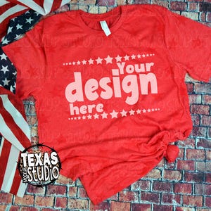 May include: A red t-shirt with the text "Your design here" in a white, playful font. The shirt is styled with an American flag and a brick background. The shirt is a mock-up from Texas Studio.