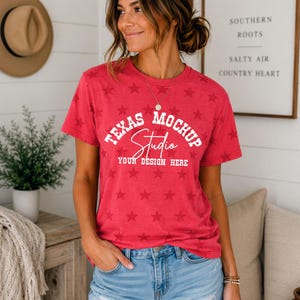May include: A red short-sleeved t-shirt featuring an all-over pattern of darker red stars. The front of the shirt displays white text that reads "TEXAS MOCHUP Studio YOUR DESIGN HERE" in a mix of block and script lettering styles.