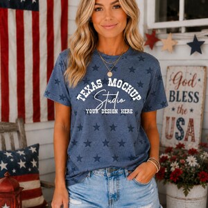 May include: A blue short-sleeved t-shirt with a repeating dark blue star pattern. The front features white text that reads TEXAS MOCHUP Studio YOUR DESIGN HERE. The shirt is paired with light blue denim shorts that have a frayed hemline.