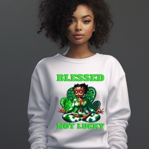 May include: White sweatshirt with a green graphic of a cartoon woman sitting in a lotus pose with the text "Blessed Not Lucky" above her.