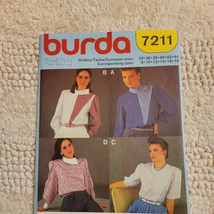 May include: A sewing pattern for a blouse with different sleeve and collar variations. The pattern is from Burda, model number 7211, and includes sizes 34-44 and 8-18. The pattern shows four different styles of the blouse, with different sleeve lengths and collar styles.
