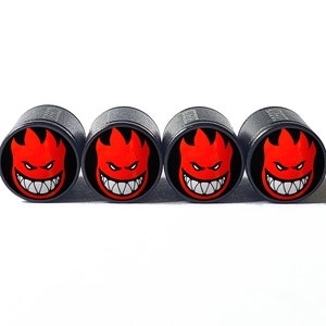 May include: Four black tyre valve stem caps with a red and white flame logo. The logo is a cartoon face with a menacing expression.