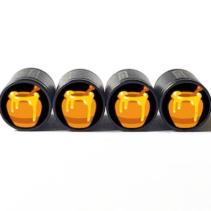 Puede incluir: Cuatro tapones de válvula negros con un diseño de tarro de miel. Cada tapón presenta un tarro de miel amarillo con un efecto de miel que gotea y un cucharón de miel de madera.