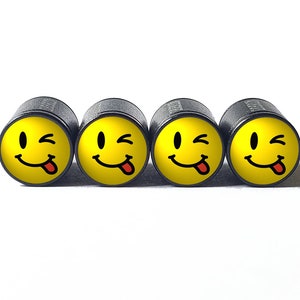 Puede incluir: Cuatro tapones de válvula negros con caras sonrientes amarillas que guiñan un ojo y sacan la lengua.