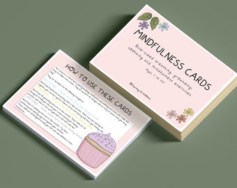 May include: A stack of pink Mindfulness Cards with floral and leaf illustrations. The cards have text that reads "Bite-sized breathing, grounding, soothing and mindfulness exercises. Ages 3 to 103." A card with instructions and a cupcake illustration is in front.