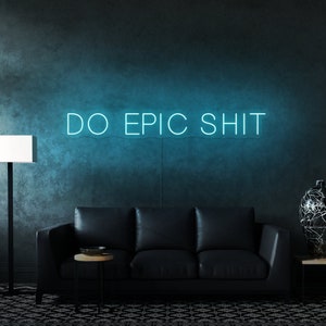 Pu&ograve; includere: Un cartello al neon blu turchese con il testo "DO EPIC SHIT" su una parete blu scuro. Un divano in pelle nera &egrave; in primo piano.