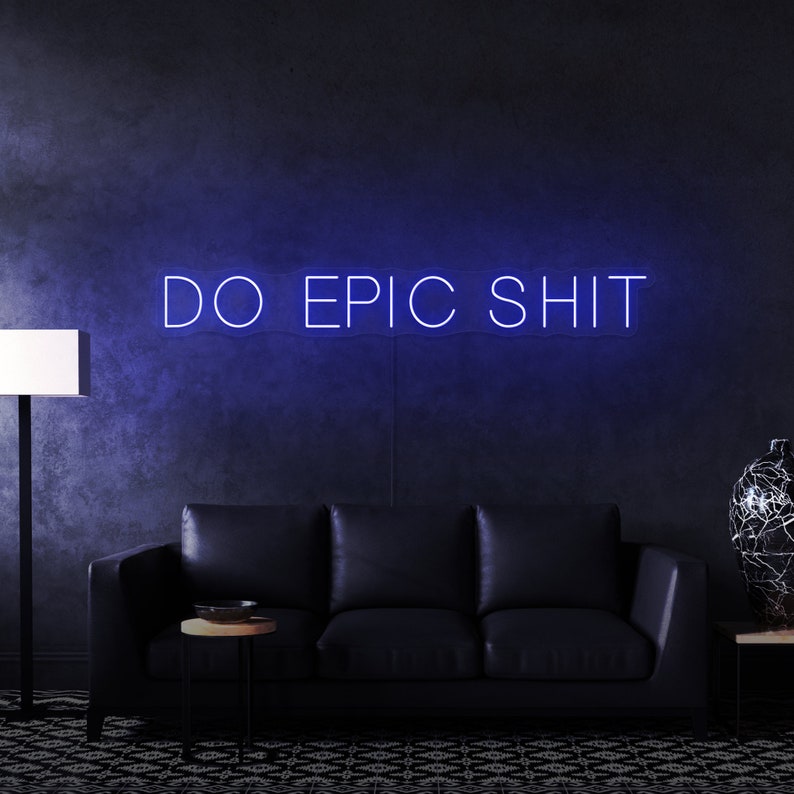 Pu&ograve; includere: Un cartello al neon blu con il testo "DO EPIC SHIT" su una parete grigio scuro. Il cartello &egrave; sopra un divano in pelle nera in un soggiorno.