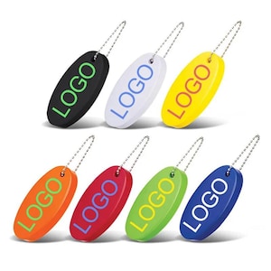 Op de afbeelding: Een verzameling ovale sleutelhangers in verschillende kleuren, waaronder zwart, wit, geel, oranje, rood, groen en blauw. Elke sleutelhanger heeft het woord "LOGO" in een contrasterende kleur en is bevestigd aan een zilveren ketting.