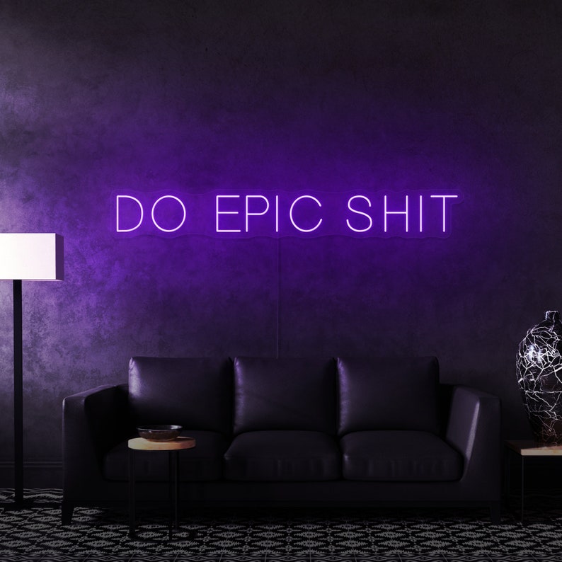 Pu&ograve; includere: Un cartello al neon viola con il testo "DO EPIC SHIT" su una parete viola scuro con un divano in pelle nera di fronte.