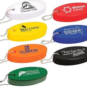 May include: A selection of oval keyrings in various colours, each with a silver chain. The keyrings feature different logos and text, including "Treasure Hills," "Women at Amazon," and "gottaglow."