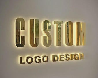 Puede incluir: En una pared clara, las palabras "CUSTOM" y "LOGO DESIGN" se muestran en letras doradas tridimensionales. Las letras están iluminadas desde atrás, creando un brillo cálido. La superficie reflectante de las letras aumenta el atractivo visual.