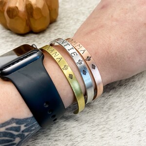 Puede incluir: Tres pulseras de oro, plata y oro rosa con los nombres grabados "NANA", "UNTIE" y "MOMMA" con un peque&ntilde;o cactus y un coraz&oacute;n.