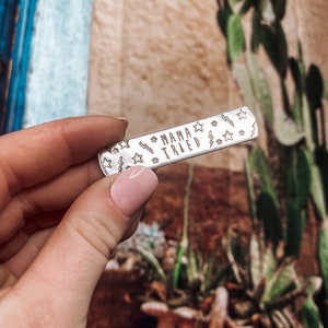 May include: Silver charm with the text "Mama Tried" surrounded by small stars and lightning bolts.