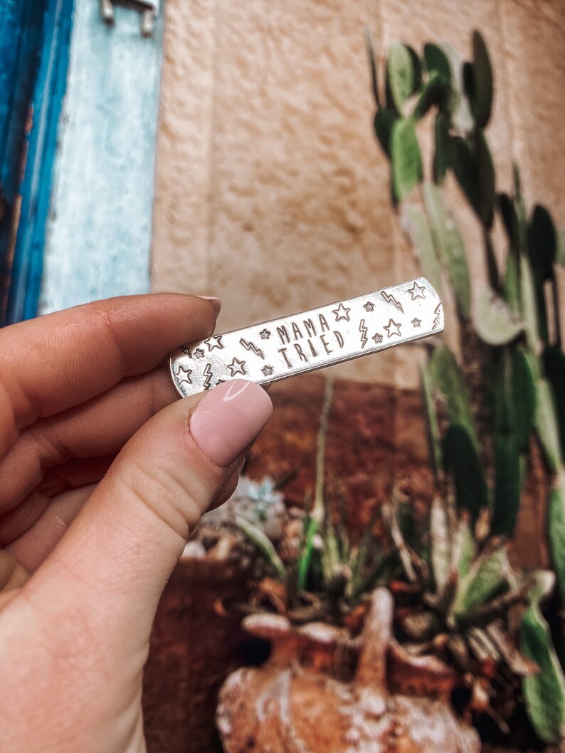 May include: Silver charm with the text "Mama Tried" surrounded by small stars and lightning bolts.