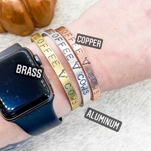May include: Four bracelets with the words "Coffee & Cows" engraved on them. The bracelets are shown in four different metal finishes: copper, brass, aluminum, and silver.