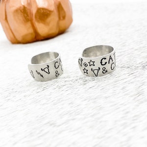 May include: Two silver rings with engraved designs. The rings feature a bull's head, stars, and the text "CAT & CO".