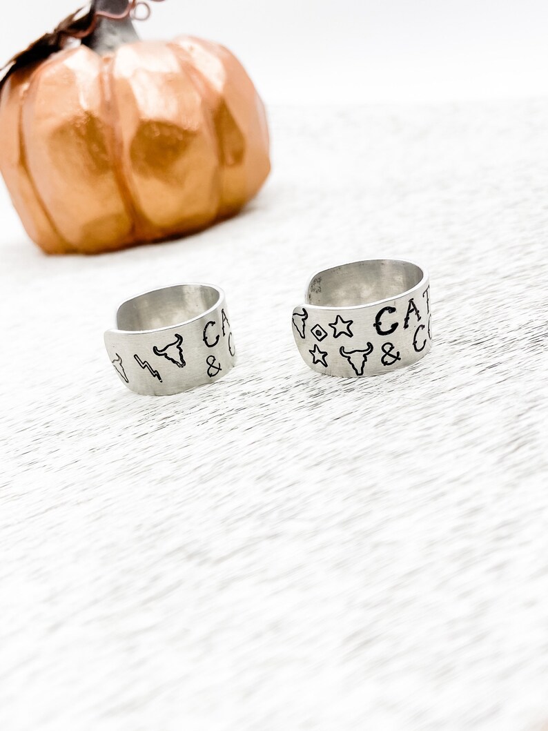 May include: Two silver rings with engraved designs. The rings feature a bull's head, stars, and the text "CAT & CO".