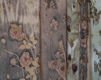 Puede incluir: Una serie de paneles de tela rectangulares con estampados botánicos en tonos marrón, gris y crema. Las superficies textiles muestran impresiones detalladas de varias hojas y flores, creando un patrón orgánico y superpuesto en la tela.