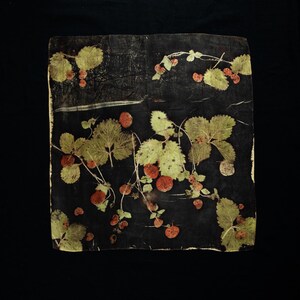 May include: A square textile piece featuring a dark black background with a botanical print of green strawberry leaves and reddish-brown berries scattered across the surface. The design displays natural plant imprints with visible veins.