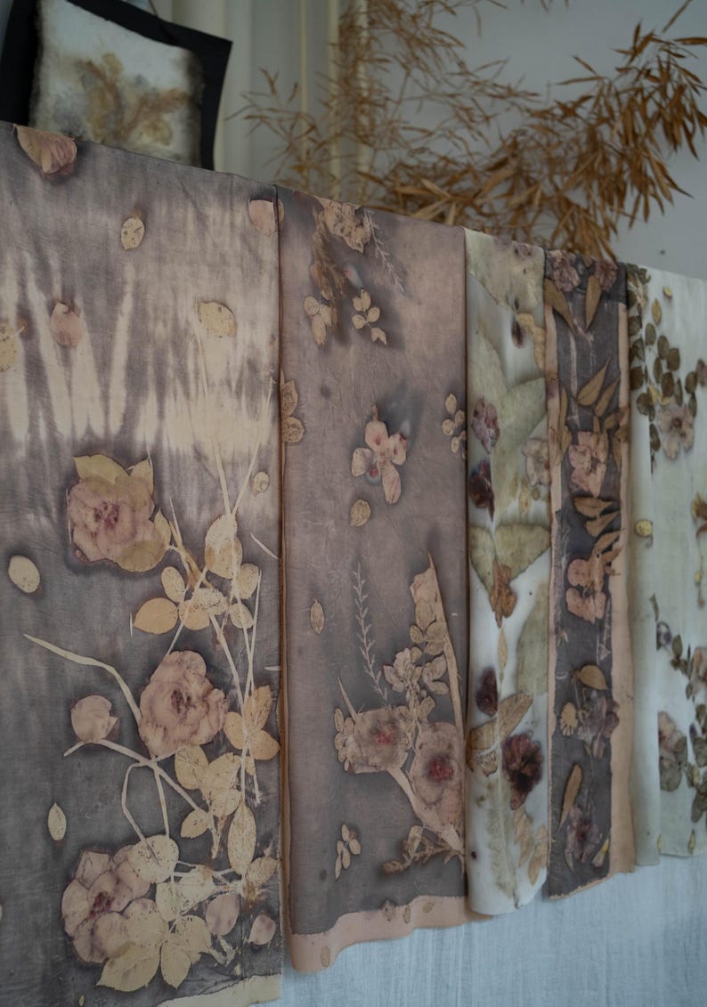 May include: A series of rectangular fabric panels featuring botanical prints in shades of muted brown, gray, and cream. The textile surfaces display detailed imprints of various leaves and flowers, creating a layered, organic pattern across the fabric.