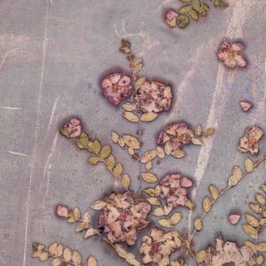 May include: A botanical print featuring pressed flowers and leaves in shades of pink, beige, and green against a muted blue-gray background. The floral arrangement includes detailed blooms and delicate foliage, creating a vintage aesthetic.