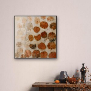 May include: A square wall art piece featuring a grid of pressed, dried leaves in shades of orange, brown, and cream. The leaves are arranged on a light, textured background and enclosed within a thin, dark frame, creating a botanical display.