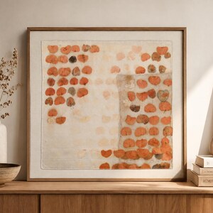 May include: A square framed wall art piece featuring a textile with a grid-like pattern of pressed orange and brown leaves. The fabric is off-white, and the leaves are arranged in rows, creating a botanical print effect within a wooden frame.