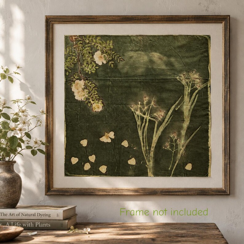 May include: A square textile wall art piece featuring botanical prints of white flowers and green foliage on a dark olive green fabric background. The artwork is displayed within a wooden frame and includes the text Frame not included.