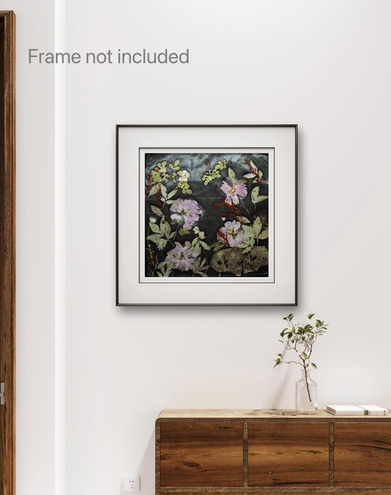 May include: A square wall art print featuring pressed flowers in shades of pink, white, and green against a dark, textured background. The artwork is displayed within a thin black frame with a white mat border. The text Frame not included is visible.