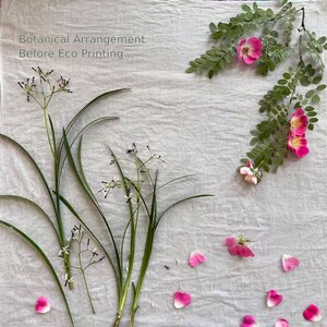 May include: A botanical arrangement on light gray fabric featuring green stems with small white flowers, a leafy branch with pink rose blossoms, and scattered pink petals. The text Botanical Arrangement Before Eco Printing is visible.
