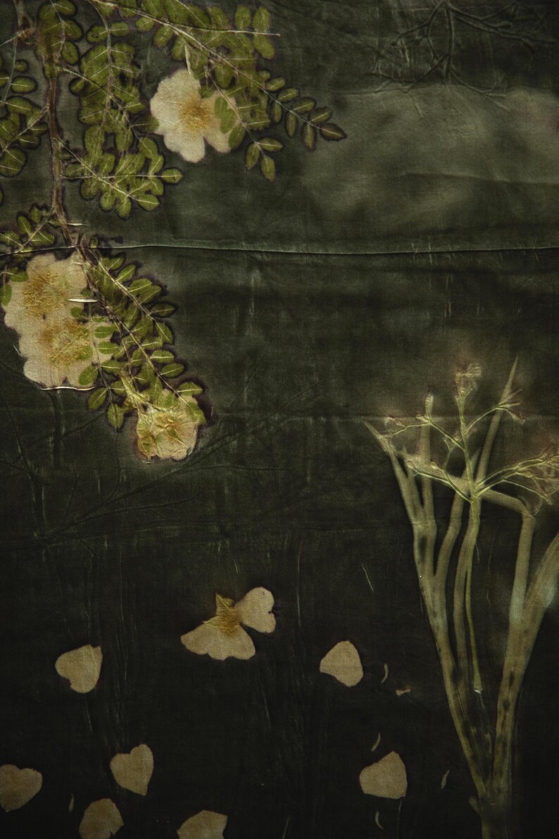 May include: A dark forest green textile featuring botanical imprints of white flowers, green leaves, and slender stems. The fabric displays a natural, organic pattern created through plant-based dyeing techniques with visible floral silhouettes.