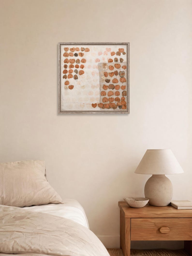 K&ouml;nnte beinhalten: Ein quadratisches Wandbild mit einem Raster aus gepressten, getrockneten braunen Bl&auml;ttern, die in einem Muster auf hellem Hintergrund angeordnet sind, eingefasst in einen d&uuml;nnen, verwitterten Holzrahmen. Die Komposition enth&auml;lt ein texturiertes Rechteck.