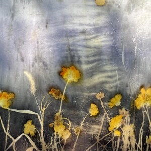 May include: A textile piece featuring a botanical print with yellow flowers and stems against a mottled, dark blue and grey background. The fabric displays a crinkled texture with a circular, light-colored shape near the top edge.