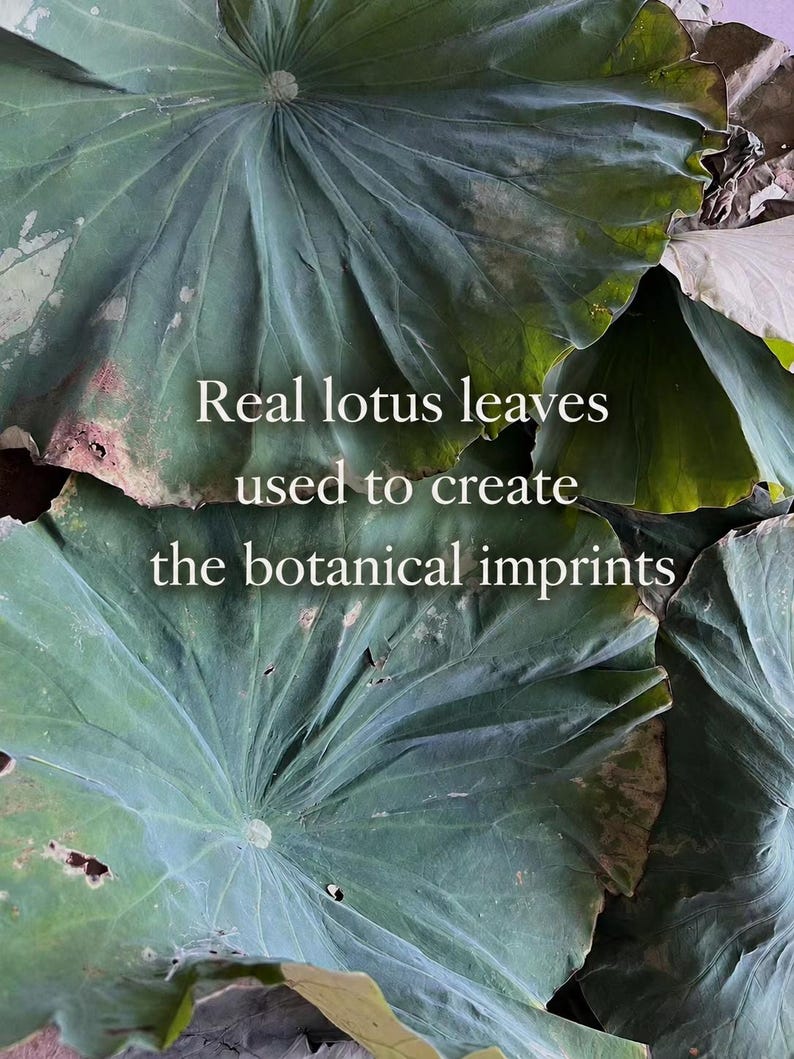 May include: A collection of large, overlapping green lotus leaves with visible veins and natural textures. The text "Real lotus leaves used to create the botanical imprints" is centered over the leaves in a clean, white, sans-serif font.