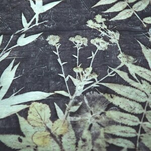 May include: A dark charcoal gray fabric featuring a botanical print with off-white silhouettes of various fern leaves and wildflower stems. The pattern displays detailed leaf structures and small flower clusters across the textile surface.